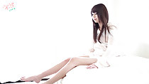 Ayana seated on bed stretching her long legs long hair down to her breasts